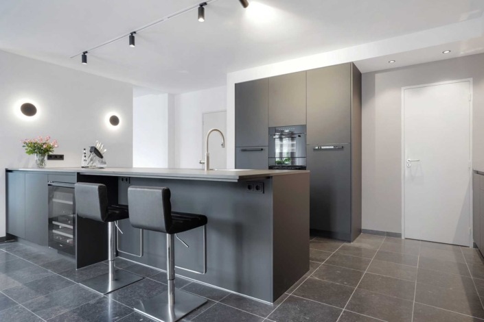 Strakke moderne keuken met granieten anticato werkblad en greeploze kasten.