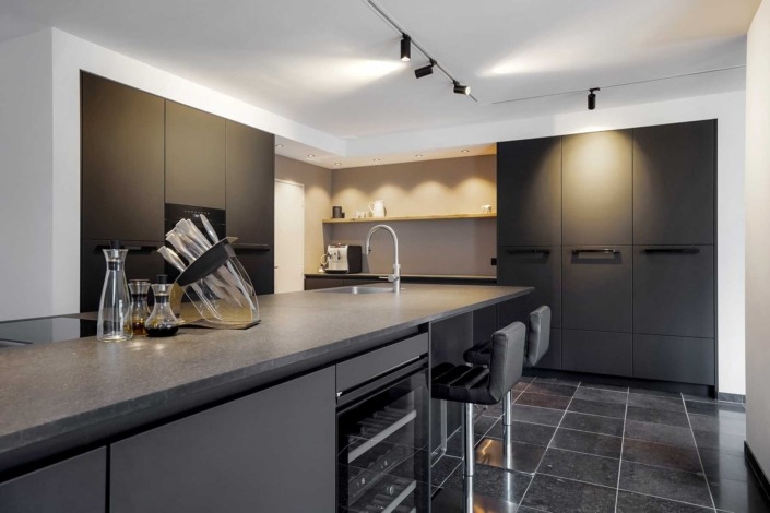 Strakke moderne keuken met granieten anticato werkblad en greeploze kasten.